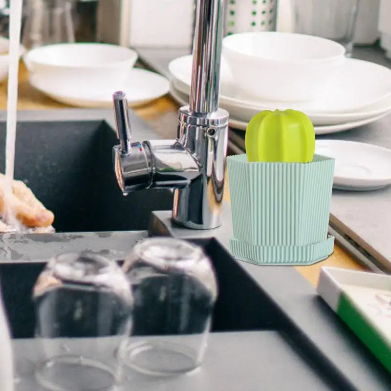 Cactus-shaped dish scrubber resting beside a faucet in a modern kitchen sink, with plates in the background.